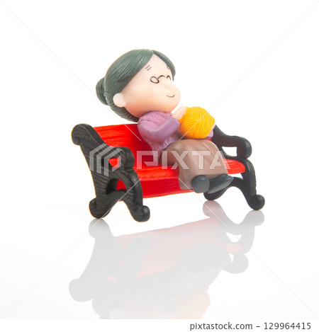 Miniature woman knitting on a red bench during a quiet afternoon Miniature woman knitting on a red bench during a quiet afternoon 129964415