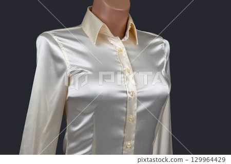Elegant silk blouse with buttons displayed on a mannequin against a dark background 129964429