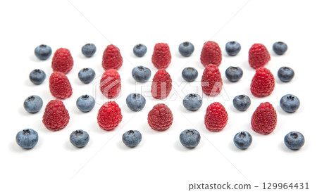 Fresh raspberries and blueberries arranged in a vibrant display on a white surface Fresh raspberries and blueberries arranged in a vibrant display on a white surface 129964431