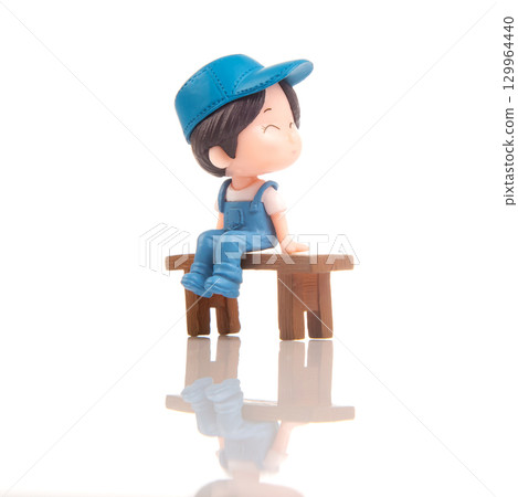 Miniature person sits happily on a wooden bench in a bright, serene environment 129964440