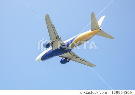 Airplane soaring high in a clear blue sky during a sunny day Airplane soaring high in a clear blue sky during a sunny day 129964509