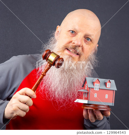 Man with a gavel and model house expresses enthusiasm for real estate auction 129964543