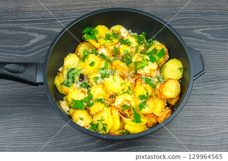 Deliciously prepared potatoes garnished with herbs on a wooden surface Deliciously prepared potatoes garnished with herbs on a wooden surface 129964565