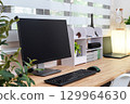 Modern and organized workspace with monitor, keyboard, laptop, shelving unit, and decorative items 129964630