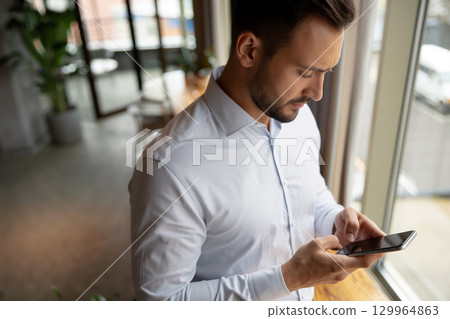 Man Checking Phone in modern office During the Morning Hours 129964863
