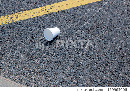 A Disposable Cup Carelessly Littered on the Asphalt Pavement 129965006