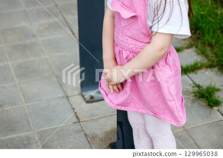 An Adorable Child Wearing a Pink Dress Standing Outdoors in Nature 129965038