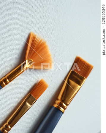Close-Up of Artist Paintbrushes Against Blank Art Canvas Surface Close-Up of Artist Paintbrushes Against Blank Art Canvas Surface 129965346