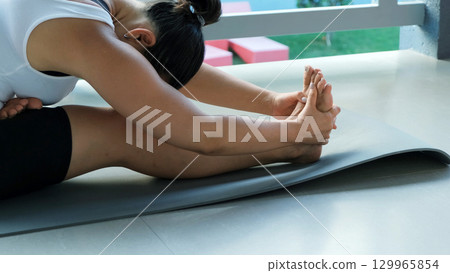 Morning yoga on balcony as young woman stretches and centers herself, embracing health and wellness in a tropical environment  129965854