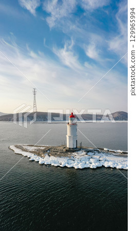 Aerial view of the lighthouse in winter in the ice at dawn 129965994