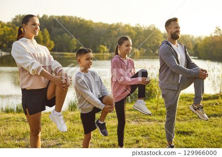 Fit and active happy parents with two kids boy and girl doing sport exercises in nature. 129966000