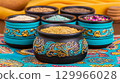 Various grains and spices are poured into pots painted with various patterns in a rustic, ethnic style. 129966028