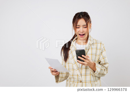Worried woman looks at phone and invoice, trying to solve financial issues and financial stress over bill payments. isolated studio white background Worried woman looks at phone and invoice, trying to solve financial issues and financial stress over bill payments. isolated studio white background 129966378
