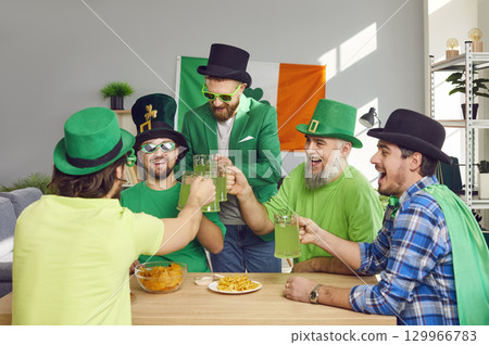Happy male friends in costumes drinking green beer and having fun at Patrick's Day party Happy male friends in costumes drinking green beer and having fun at Patrick's Day party 129966783