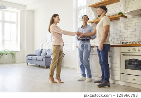 Couple, real estate agent hand shake deal in modern indoor space, professional consultation, focused 129966788