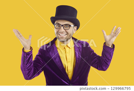 Funny entertainer in purple suit and hat presents circus show, spreads hands and smiles Funny entertainer in purple suit and hat presents circus show, spreads hands and smiles 129966795