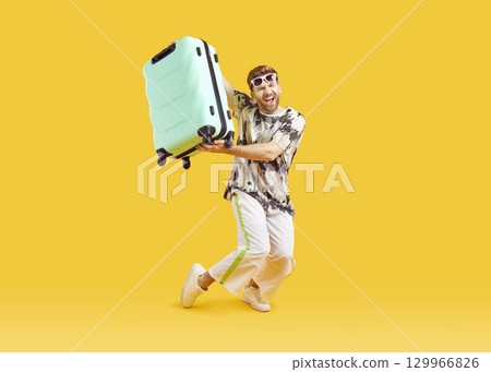Funny young man in sunglasses with suitcase is going on summer holiday on yellow background. Funny young man in sunglasses with suitcase is going on summer holiday on yellow background. 129966826