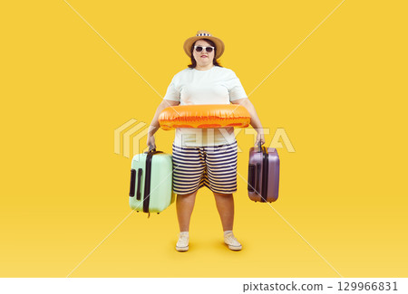 Excited plus size standing with suitcases and inflatable ring going on vacation Excited plus size standing with suitcases and inflatable ring going on vacation 129966831