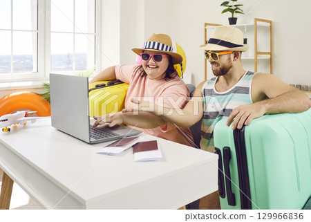 Funny couple planning vacation trip while sitting at home with packed suitcases 129966836