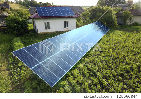 Aerial view of a house with blue solar panels for clean energy. 129966844