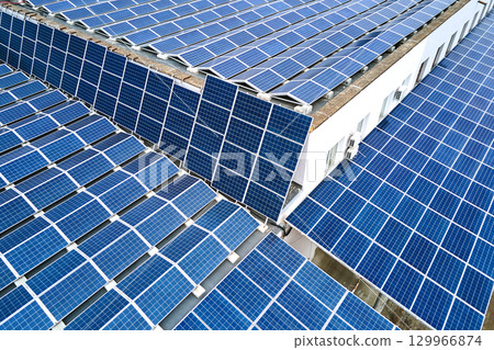 Aerial view of solar power plant with blue photovoltaic panels mounted on industrial building roof for producing green ecological electricity. Production of sustainable energy concept. Aerial view of solar power plant with blue photovoltaic panels mounted on industrial building roof for producing green ecological electricity. Production of sustainable energy concept. 129966874