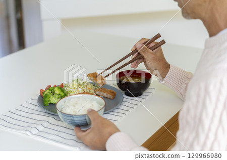 一位 60 多歲男士正在吃炸豬排的手 129966980