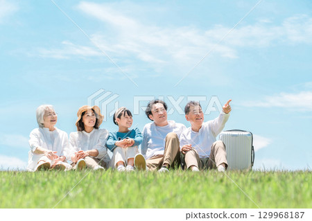 一個可以看到藍天的公園，一個坐在山上的家庭，父母和孩子，一個三代家庭（父親，母親，女兒，祖母，祖父） 129968187