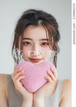 [Vertical photo] A woman holding a heart-shaped object 129968229