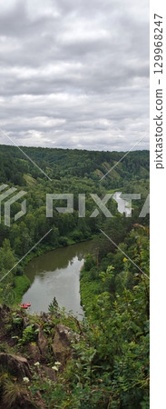 Idyllic River Bend Through Verdant Forest Under Cloudy Sky, Perfect for Outdoor Adventures 129968247