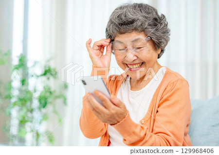 Senior woman looking at smartphone screen Senior woman looking at smartphone screen 129968406