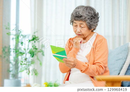 Senior woman holding bankbook worried 129968419