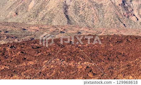 The stunning desert terrain features beautifully textured red soil accompanied by rocky mountains 129968618