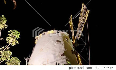 An Illuminated Windmill at Night Surrounded by Beautiful Trees in a Charming Landscape An Illuminated Windmill at Night Surrounded by Beautiful Trees in a Charming Landscape 129968656