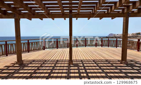 Enjoy a scenic ocean view from a lovely wooden deck with a stylish pergola, perfect for relaxation 129968675