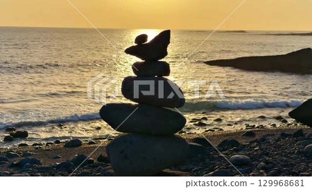 A Serene Sunset Overlooking the Calm Beach Accompanied by Balanced Stones and Tranquility A Serene Sunset Overlooking the Calm Beach Accompanied by Balanced Stones and Tranquility 129968681
