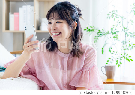 A young woman operating a smartphone 129968762
