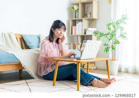 A woman using a computer in the living room 129968817