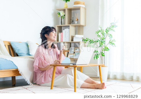 A woman using a computer in the living room A woman using a computer in the living room 129968829