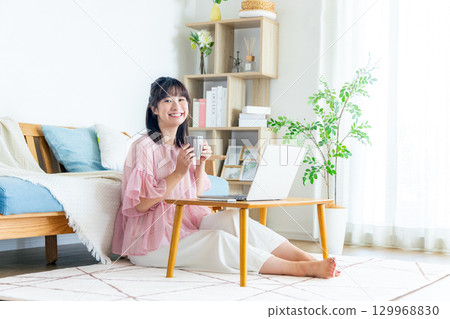 A woman using a computer in the living room A woman using a computer in the living room 129968830