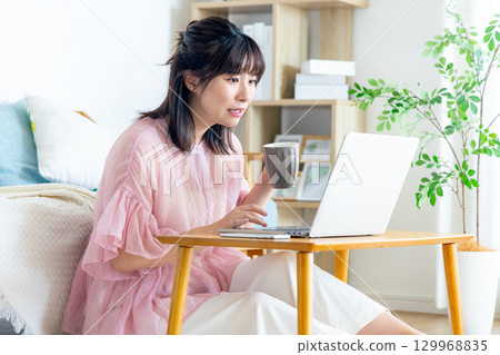 A woman using a computer in the living room A woman using a computer in the living room 129968835