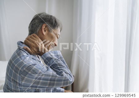 Senior man in pajamas holding his neck in pain Senior man in pajamas holding his neck in pain 129969545