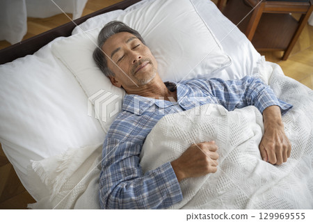 一名 60 多歲的男子在床上睡覺 一名 60 多歲的男子在床上睡覺 129969555