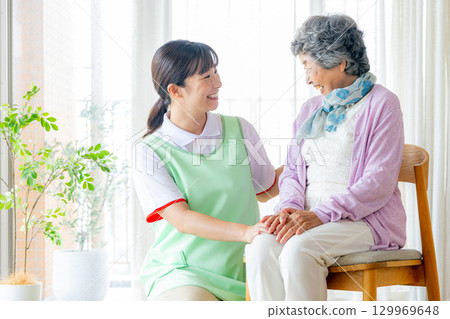 A female caregiver and a young caregiver sitting on a chair 129969648