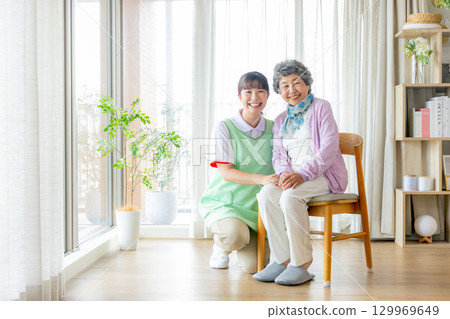 A female caregiver and a young caregiver sitting on a chair A female caregiver and a young caregiver sitting on a chair 129969649