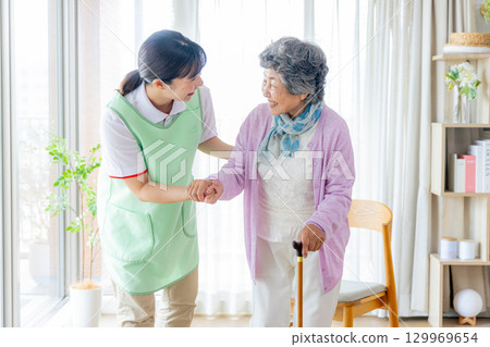 護理形象：老年婦女和護理人員拄著拐杖行走 129969654