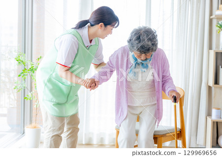護理形象:老年婦女和護理人員拄著拐杖行走 護理形象:老年婦女和護理人員拄著拐杖行走 129969656