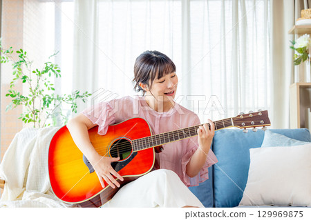 A young lady playing the guitar 129969875