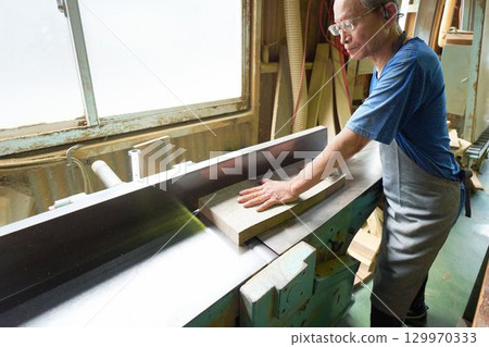 Elderly craftsman working in a woodworking shop 129970333