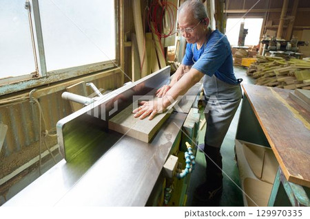 An elderly woodworker carving wood 129970335