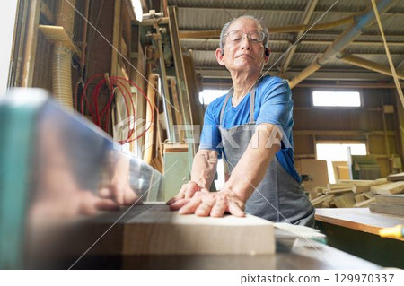 An elderly woodworker carving wood An elderly woodworker carving wood 129970337